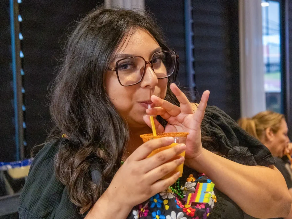 A woman drinking juice at Houston training session venue - Up Above Venue