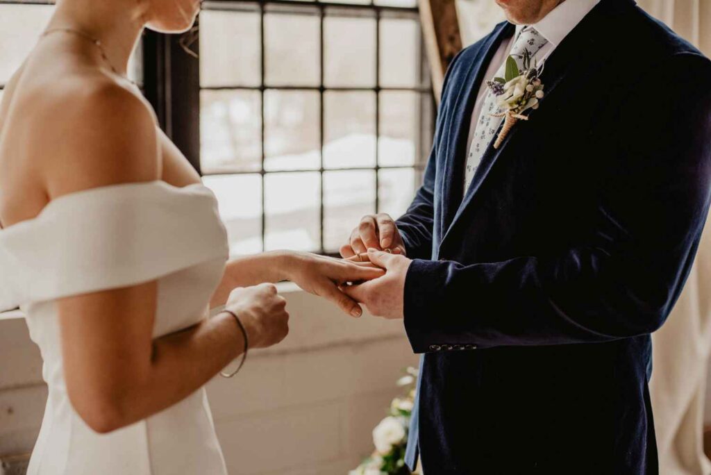 A groom helping his wife to wear a ring - Up Above Venue